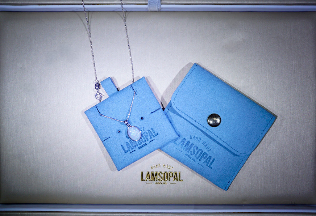 Blue jewelry packaging with a opal necklace on a gold background, featuring the brand 'Lamsopal'.