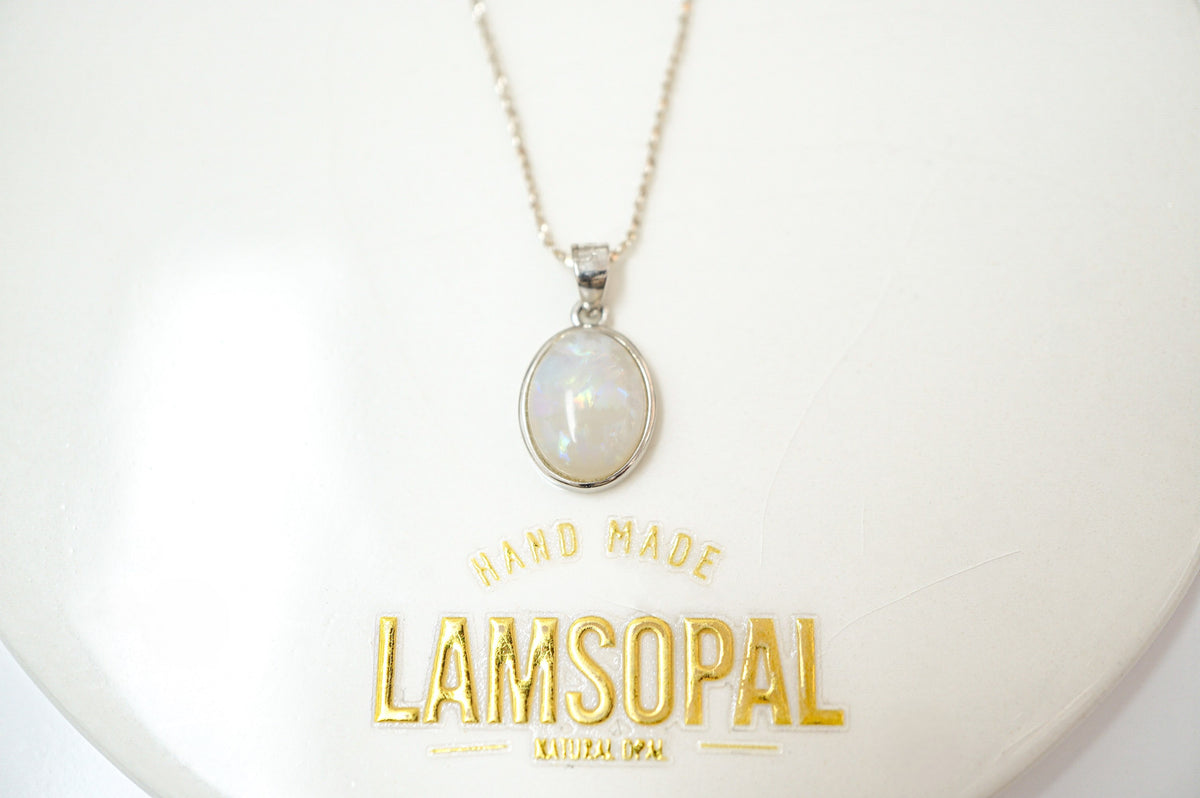 A silver chain necklace with an oval iridescent white pendant displayed on a white surface with gold 'LAMSOPAL HAND MADE' branding below.