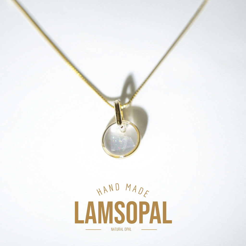 A gold chain necklace with a circular pendant featuring a milky white iridescent stone, displayed on a clean white background with 'HAND MADE LAMSOPAL NATURAL OPAL' text below.