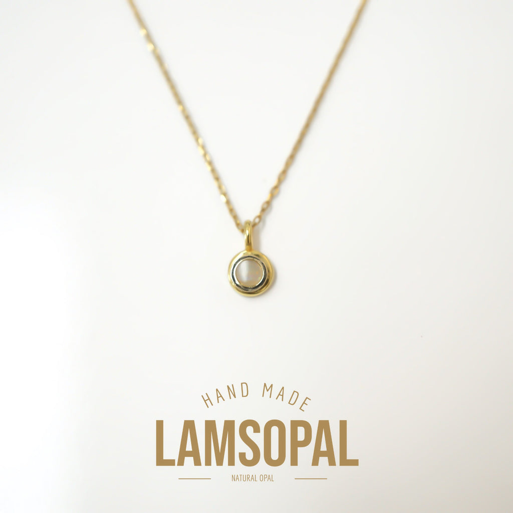 A delicate gold chain necklace with a small circular pendant featuring a natural white opal in a bezel setting, displayed on a clean white background with 'LAMSOPAL' branding printed below.