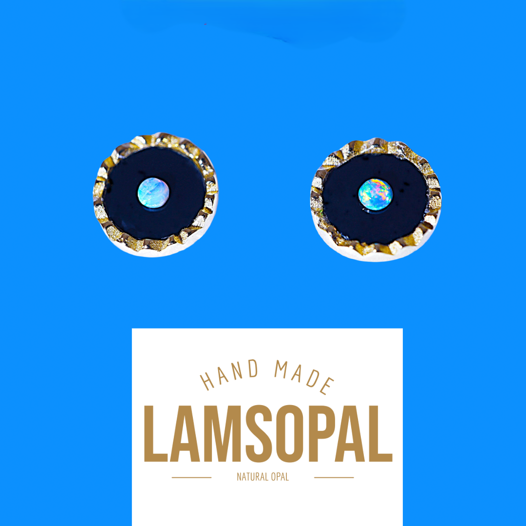 Two handmade circular stud earrings with iridescent blue opal centers and textured gold-rimmed edges, shown above a white label reading 'HAND MADE LAMSOPAL NATURAL OPAL' on a bright blue background.