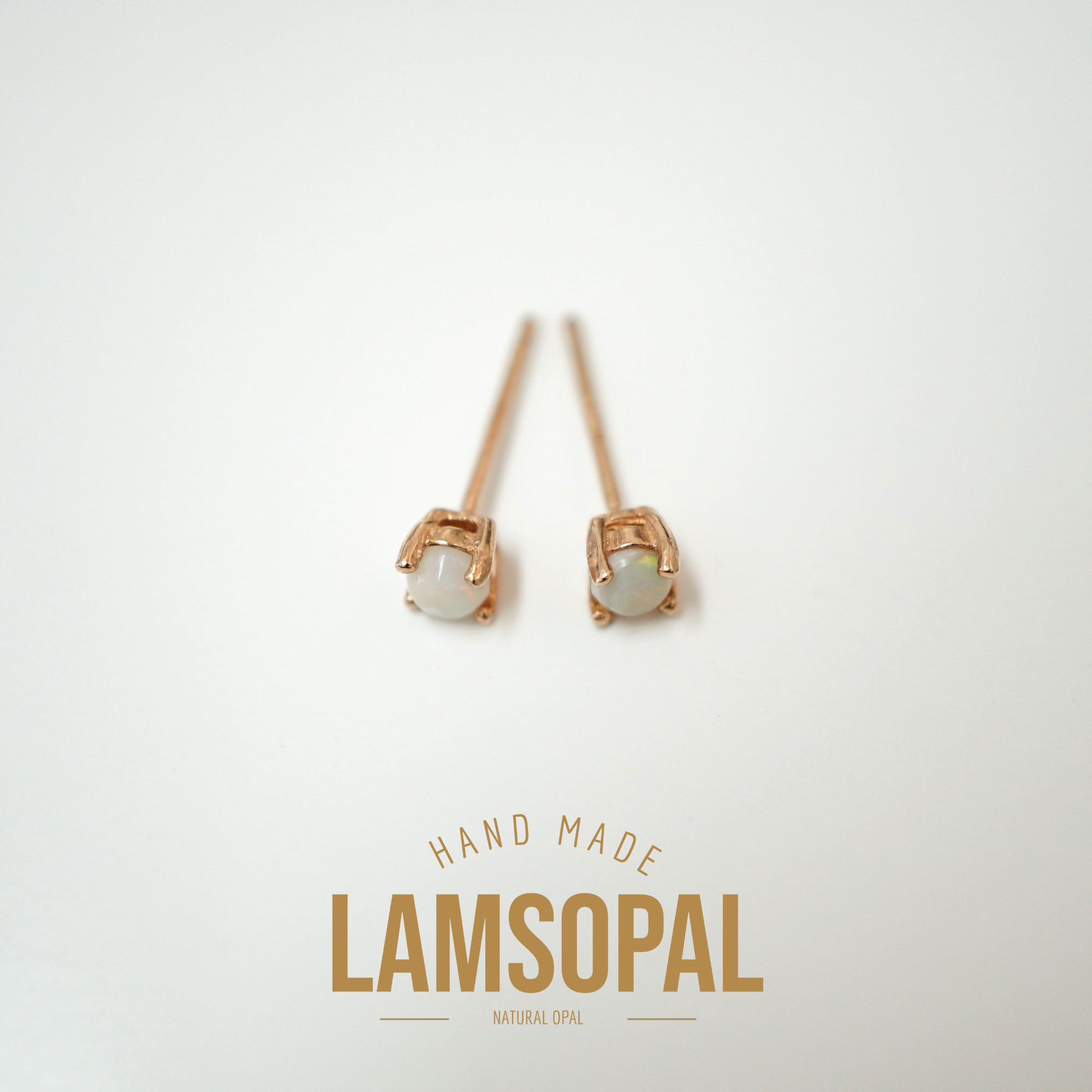 A pair of handmade stud earrings with oval natural opal gemstones in rose gold settings, displayed on a clean white background with a gold 'LAMSOPAL' brand logo below.