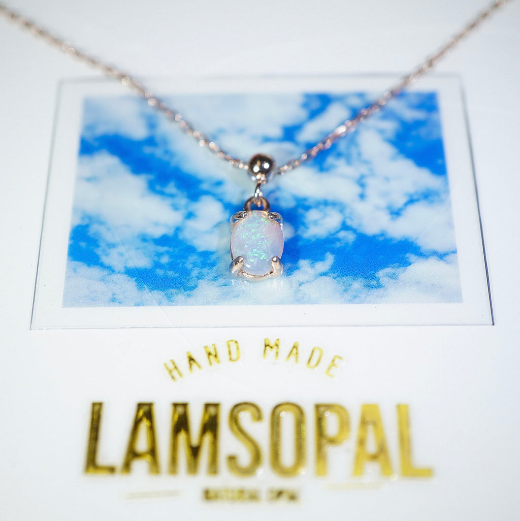 A silver chain necklace with a small iridescent white pendant displayed on a printed card that says HAND MADE LAMSOPAL, against a white background.