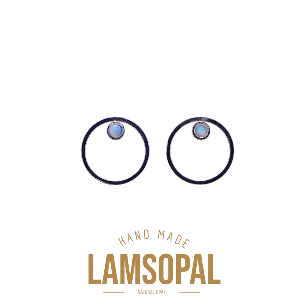 A pair of Lamsopal hand-made natural opal hoop earrings with a dark metal rim and a round light blue opal center, shown on a white background with 'HAND MADE LAMSOPAL NATURAL OPAL' text below.