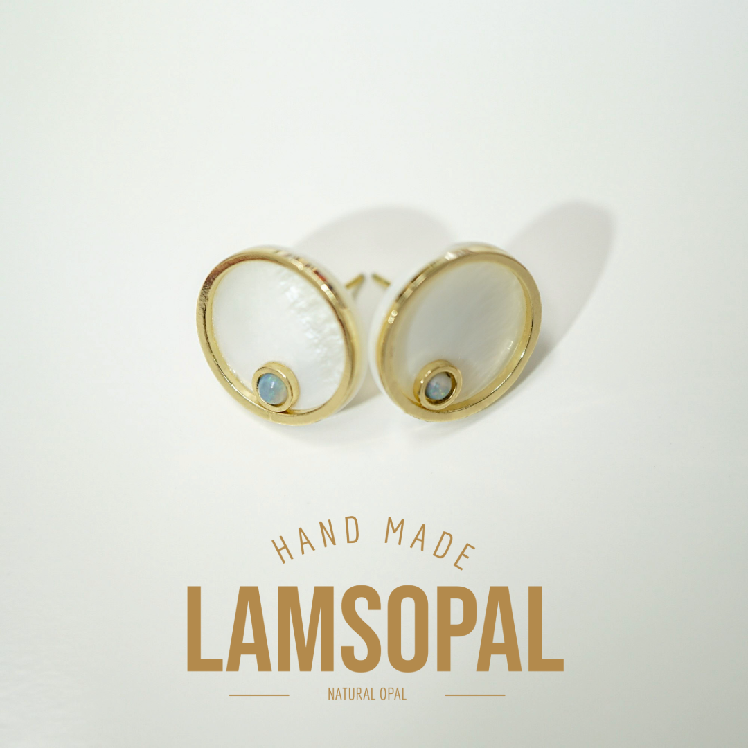 A pair of gold-tone stud earrings with circular white mother-of-pearl inlays and a small light blue opal stone at the bottom, displayed on a clean white background with the text 'HAND MADE LAMSOPAL NATURAL OPAL' below.