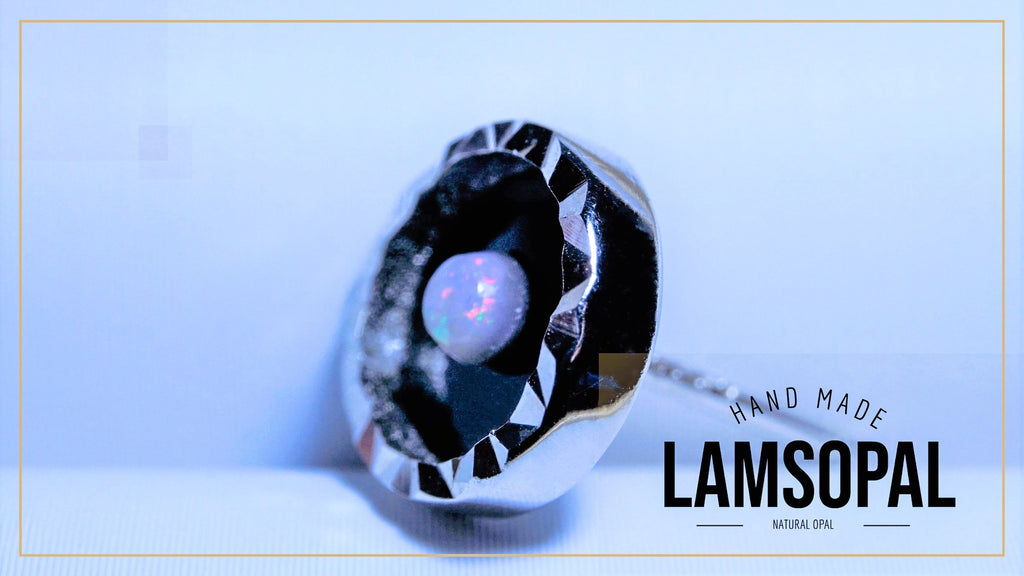 A faceted silver pendant featuring a round natural opal gemstone with iridescent colors, displayed on a light blue background with 'HAND MADE LAMSOPAL' text overlay.
