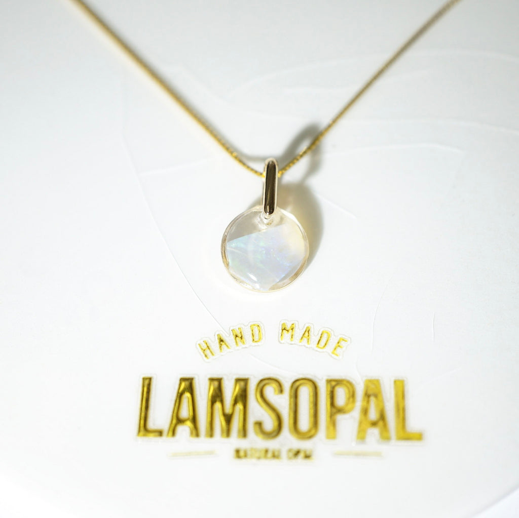 A gold chain necklace with a round iridescent moonstone pendant, displayed on a white backing card with gold foil text reading 'HAND MADE LAMSOPAL'.