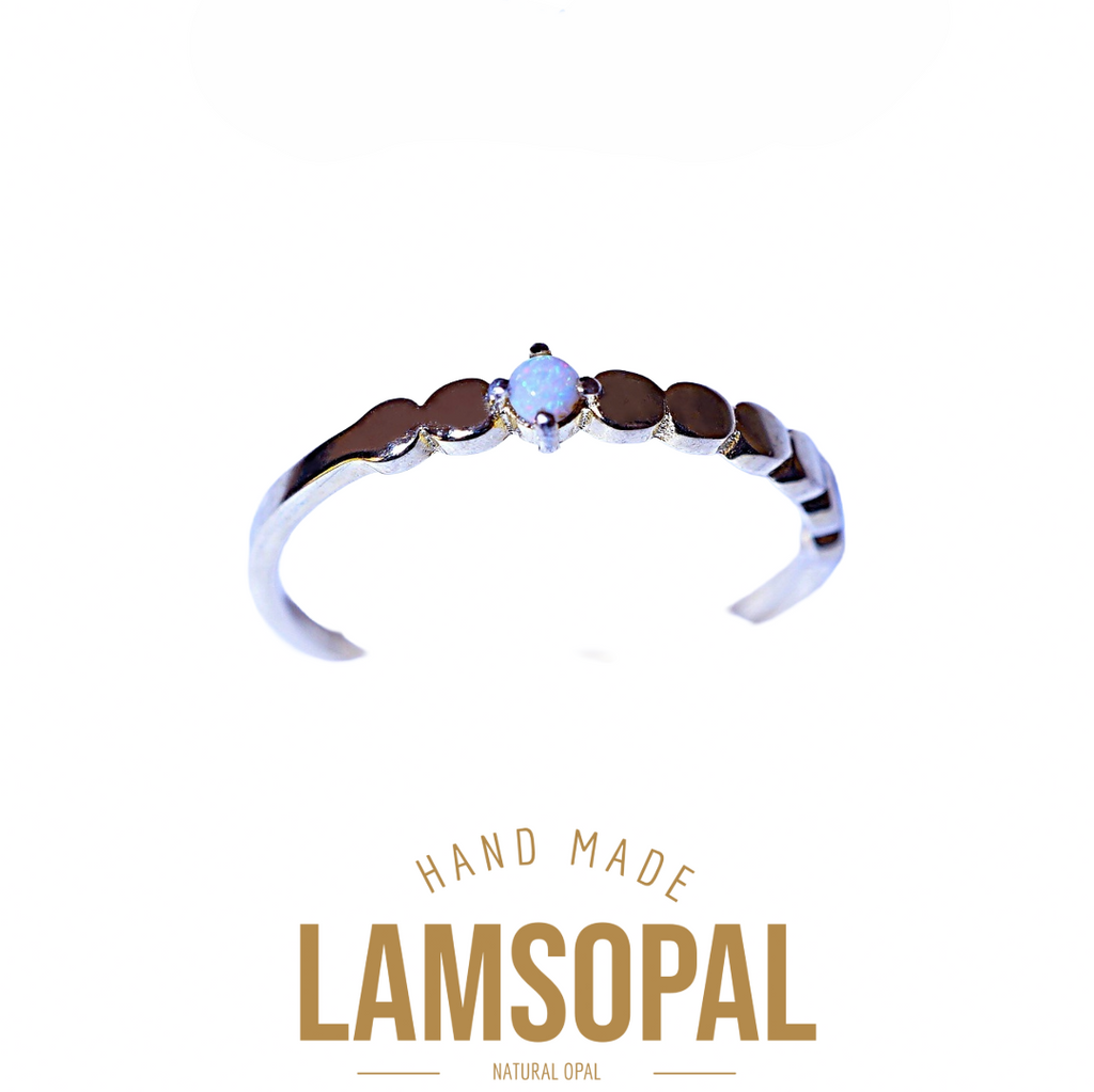 A silver-toned open ring band featuring a central natural opal gemstone and a row of dark brown inlay stones, shown on a white background with 'LAMSOPAL' branding and 'HAND MADE' text below.