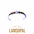 A silver-toned open ring band featuring a central natural opal gemstone and a row of dark brown inlay stones, shown on a white background with 'LAMSOPAL' branding and 'HAND MADE' text below.