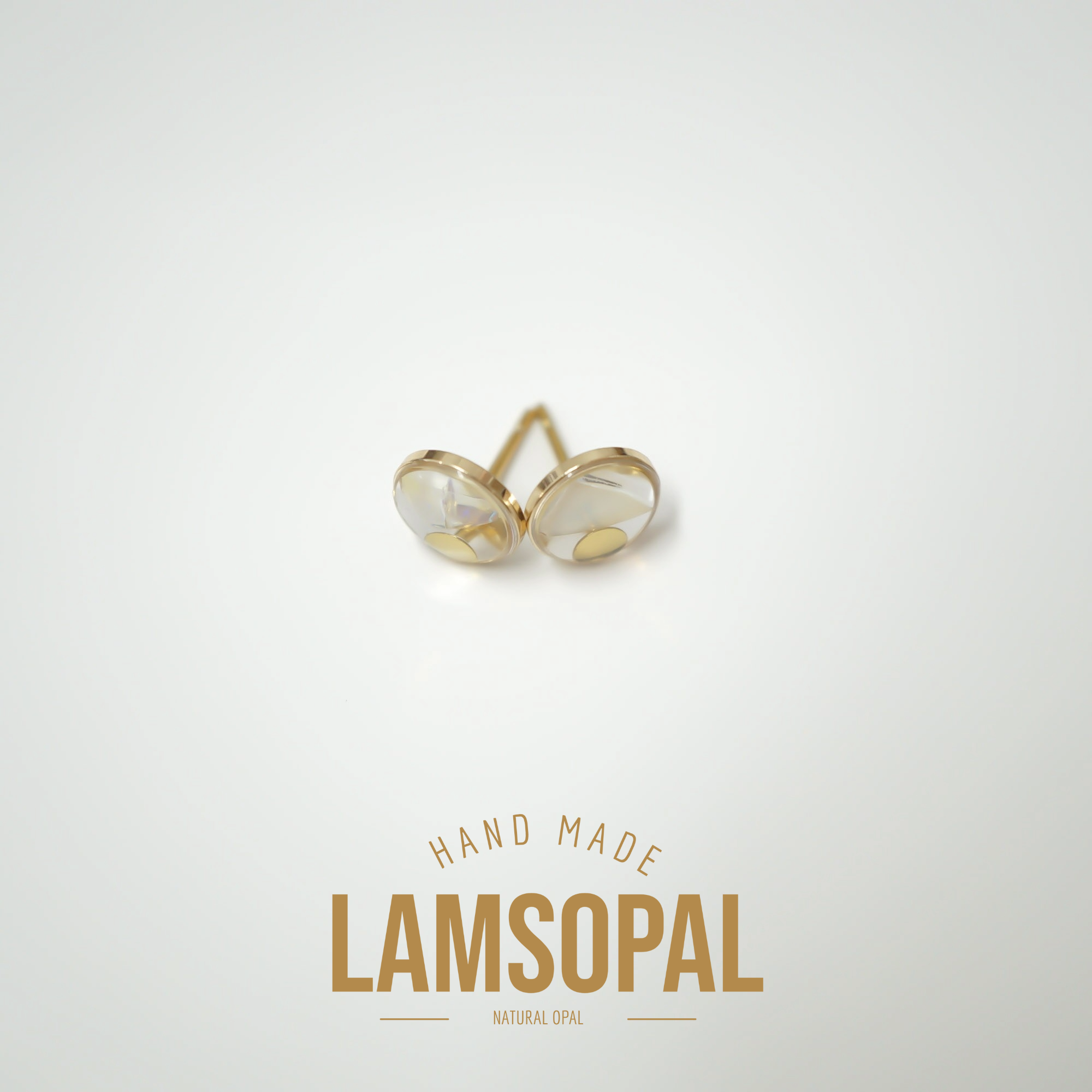 A pair of gold heart-shaped stud earrings with natural opal inlays, displayed on a clean white background with 'HAND MADE LAMSOPAL' text below.