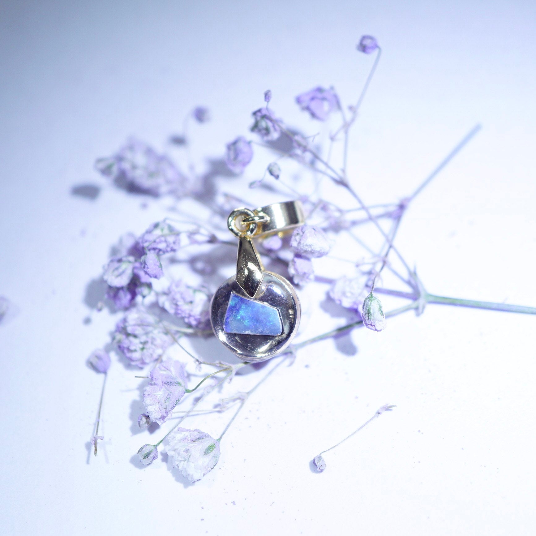Gold plated pendant with opal gemstone on a white background