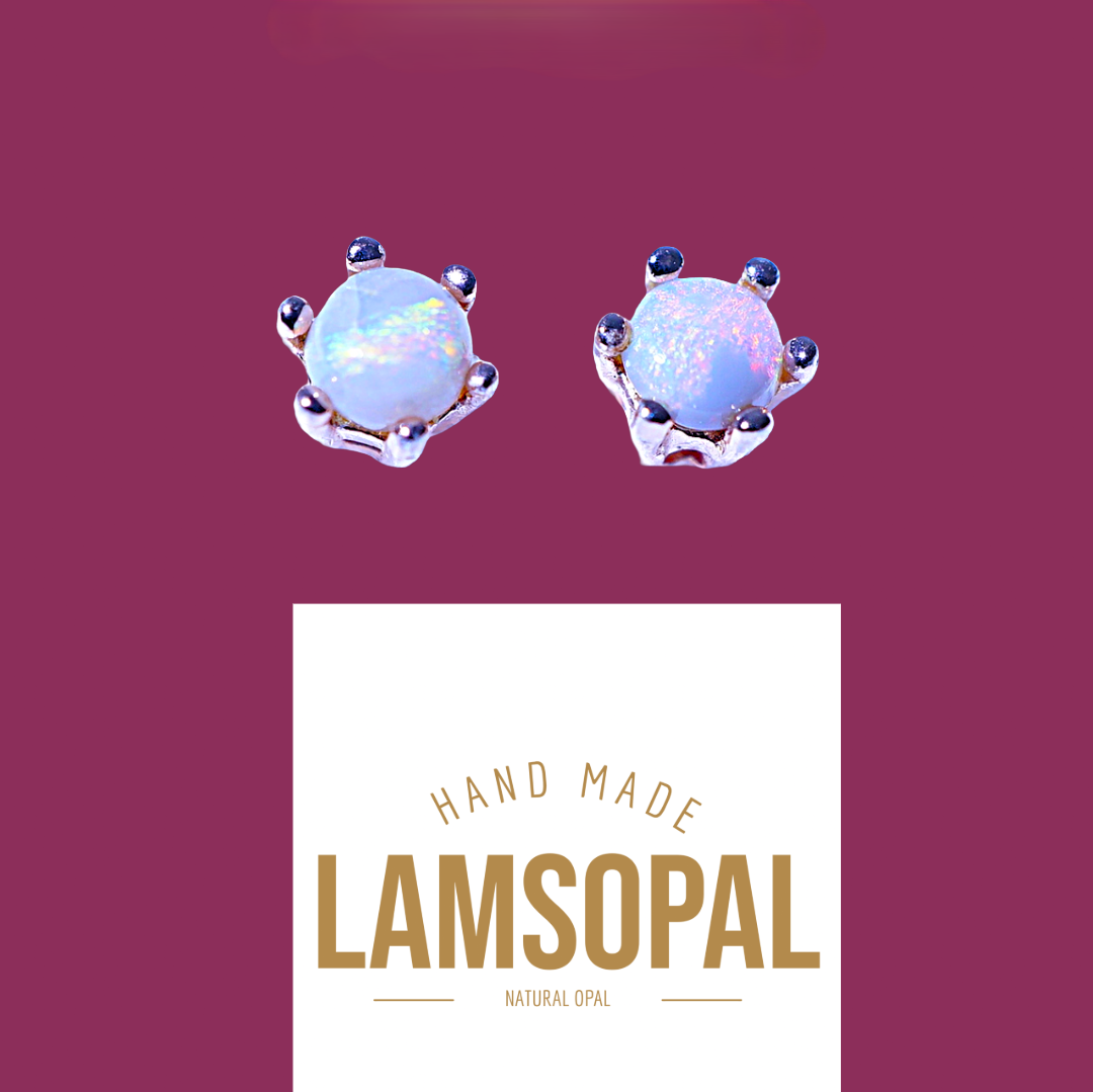 A pair of handmade stud earrings featuring round iridescent white opal gemstones in a silver-toned claw setting, displayed above a white card with the brand name 'LAMSOPAL' on a solid dark magenta background.