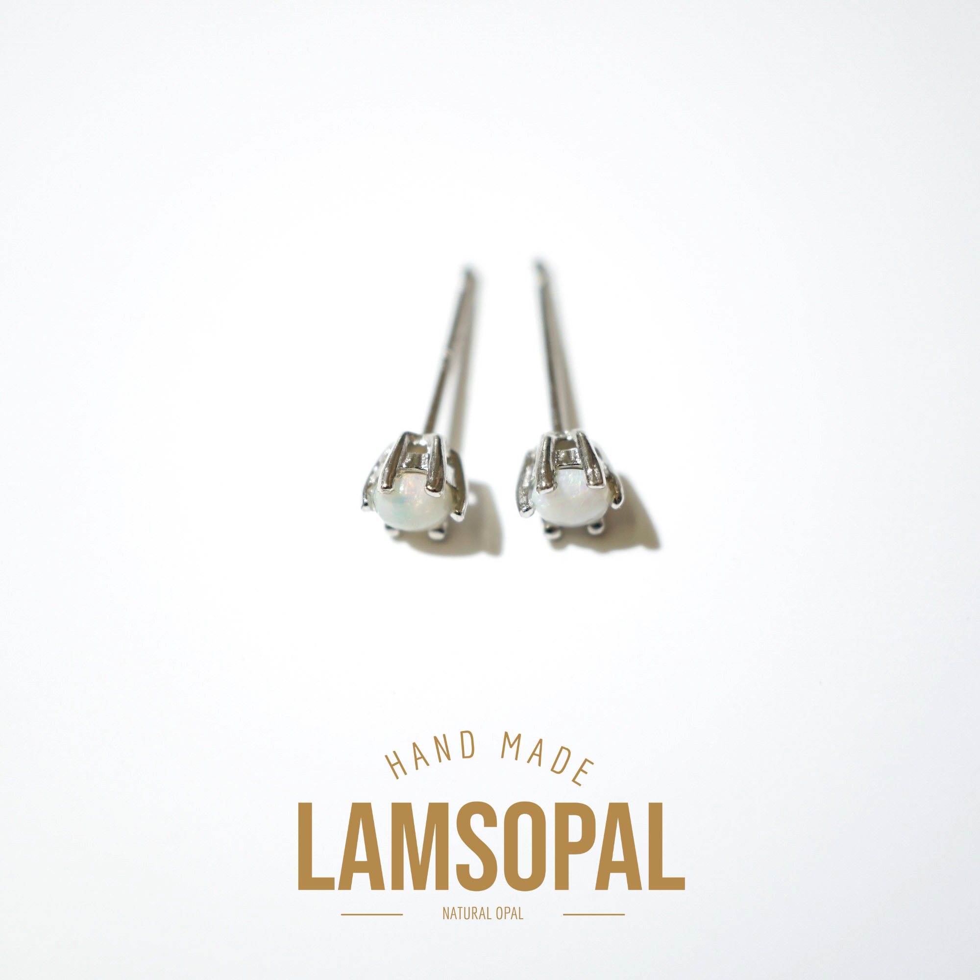 A pair of silver-toned stud earrings with oval white opal-like centers, displayed on a clean white background with the text 'HAND MADE LAMSOPAL NATURAL OPAL' below.