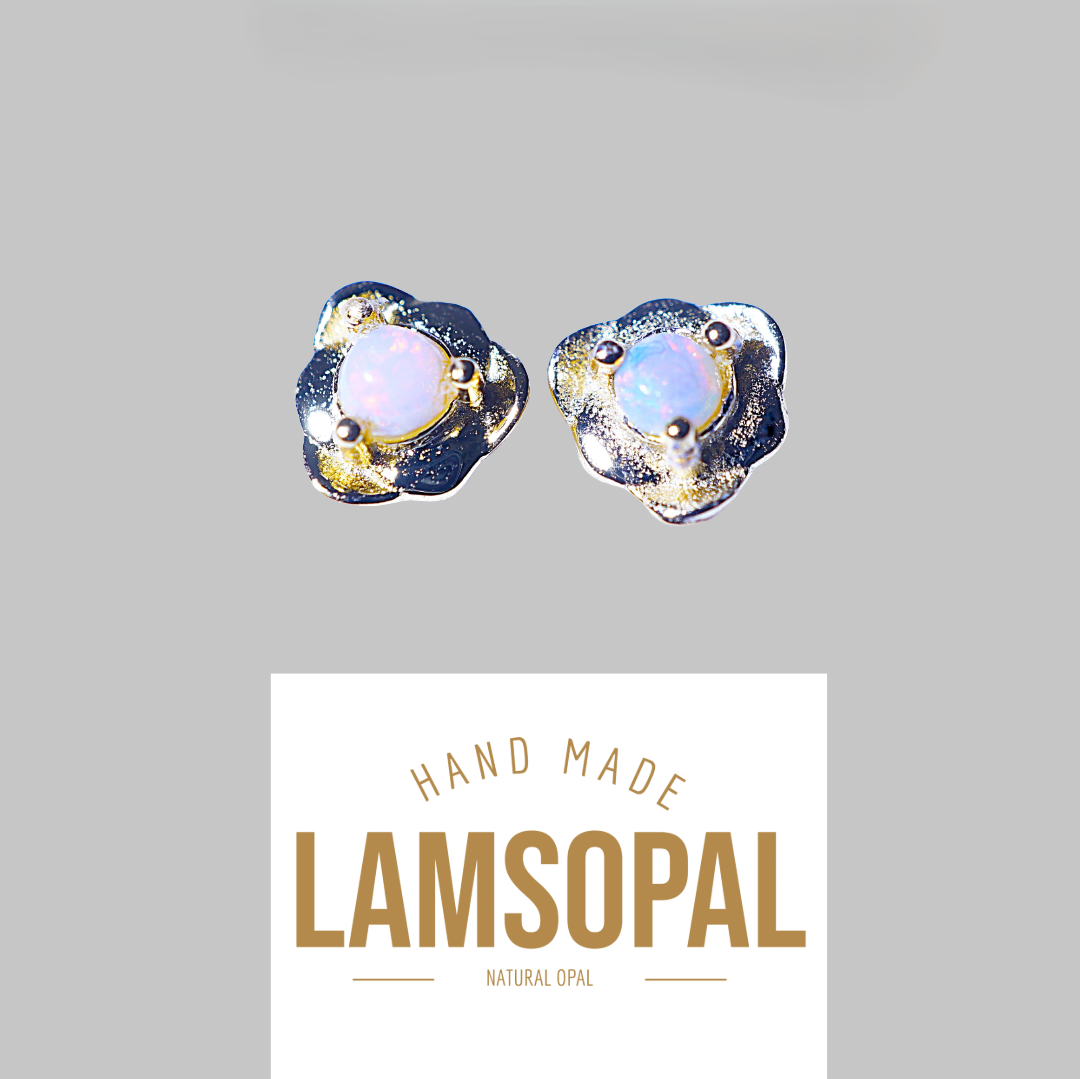 A pair of handmade Lamsopal natural opal stud earrings with textured gold and silver settings, shown above a white brand card on a solid gray background.