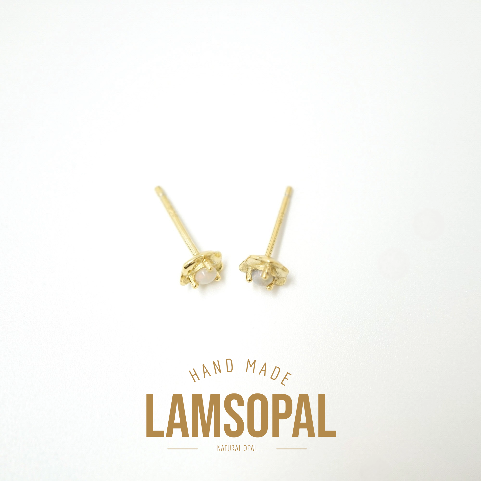 A pair of small gold stud earrings with natural opal centers, displayed on a clean white background with a gold 'LAMSOPAL' brand logo and 'HAND MADE' text below.