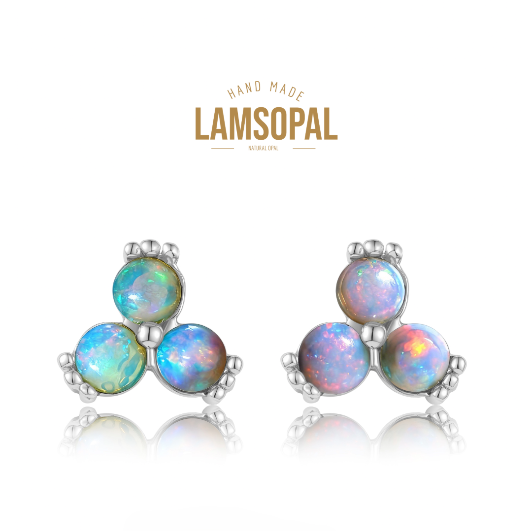 A pair of Lamsopal handmade earrings featuring three round iridescent opal gemstones in a triangular cluster, set in silver-toned metal, shown on a white background with a reflection and the brand logo above.
