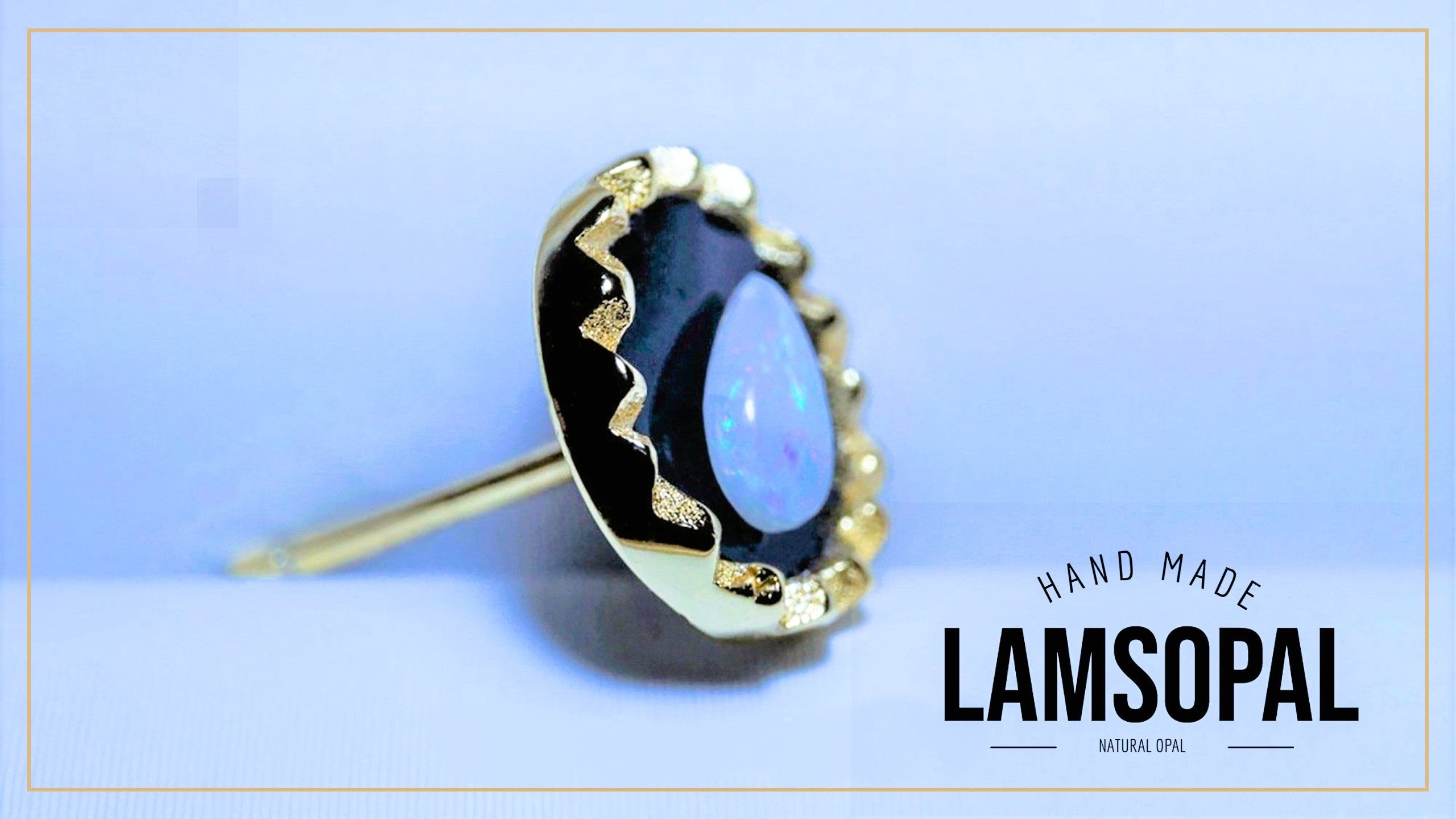 A gold-toned Lamsopal stud earring featuring a natural opal with a black inlay, displayed on a light blue background with a gold border and 'HAND MADE LAMSOPAL' text overlay.