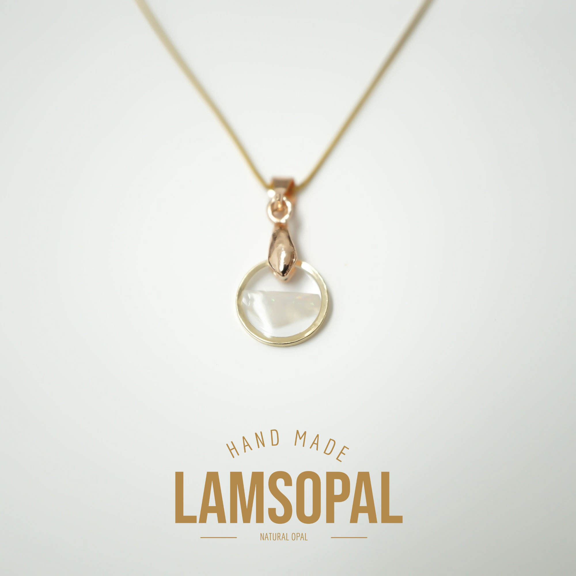 A delicate gold necklace with a teardrop-shaped clear gemstone pendant, displayed on a clean white background with 'HAND MADE LAMSOPAL' text below.