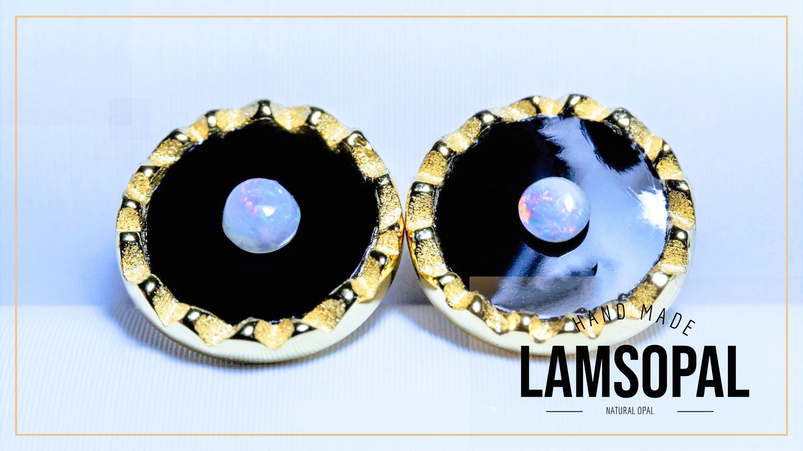 A pair of handmade Lamsopal natural opal stud earrings with gold bezel settings and black inlays, displayed on a light blue background with a gold border. The text 'LAMSOPAL' is visible in the bottom right corner.