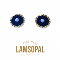 A pair of Lamsopal natural opal stud earrings with a deep blue bezel setting and a textured gold-toned scalloped rim, featuring a central iridescent blue-white opal. The brand name 'LAMSOPAL' is displayed below the earrings on a clean white background.