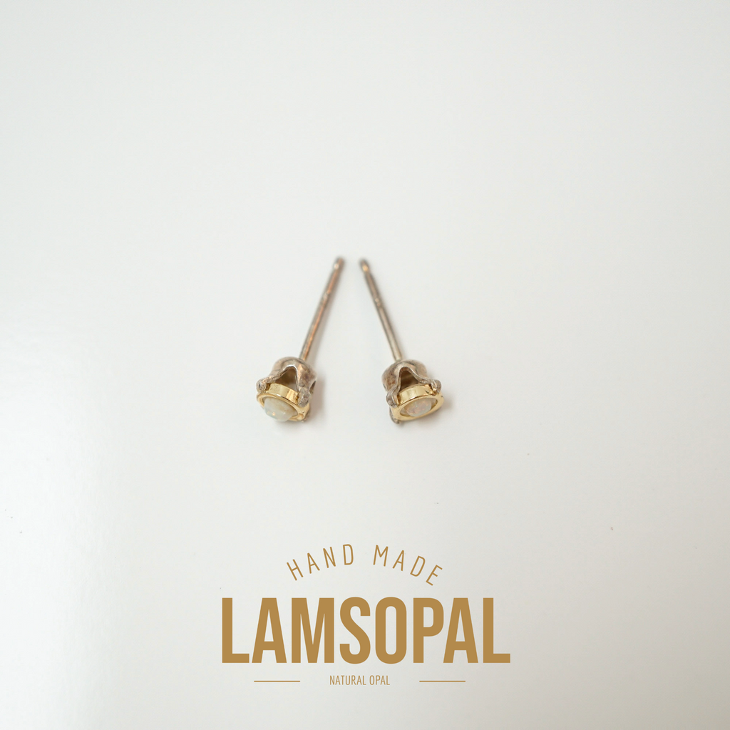 A pair of small gold stud earrings with oval cream-colored stones, displayed on a clean white background with a 'LAMSOPAL' brand logo at the bottom.
