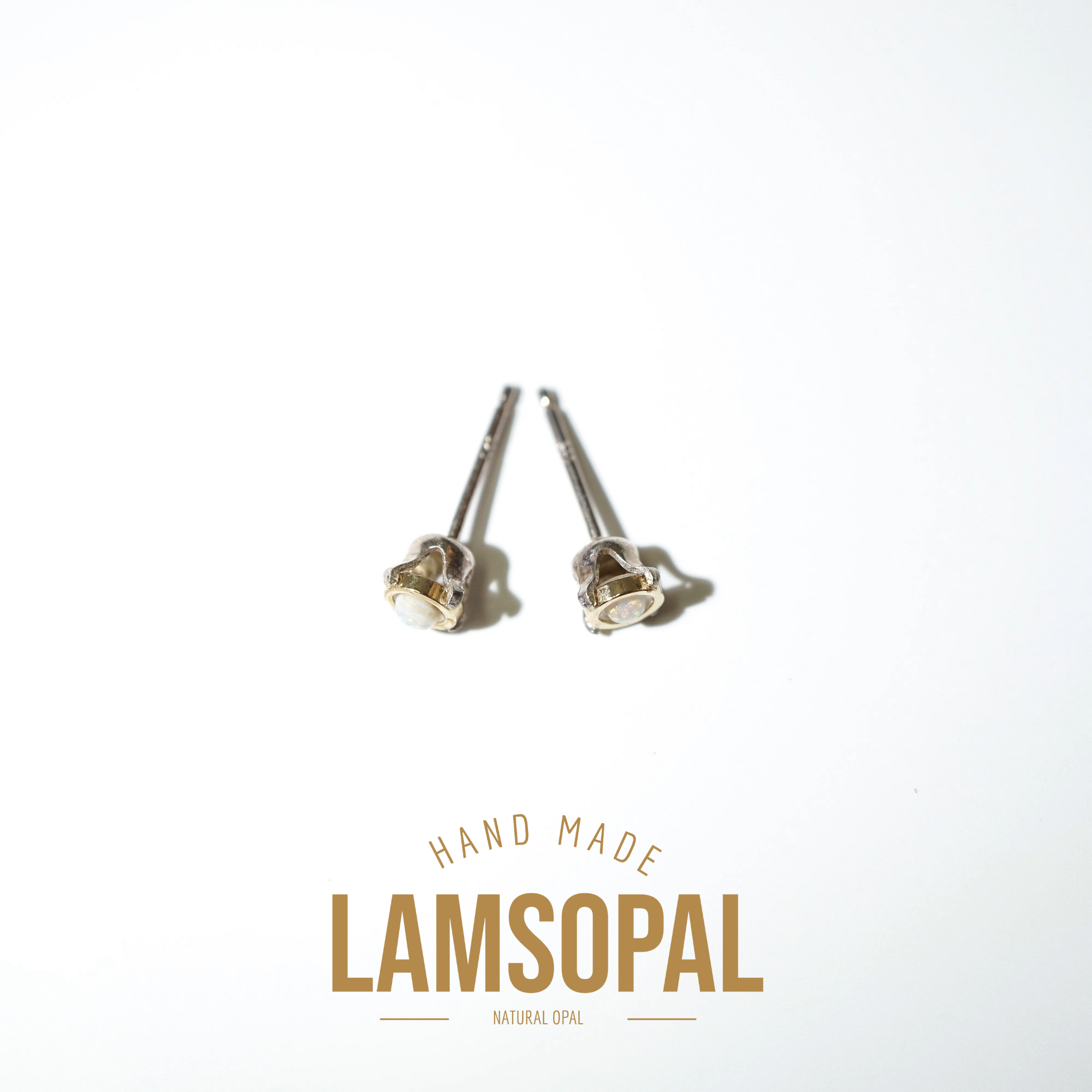 A pair of handmade Lamsopal natural opal stud earrings with silver posts, displayed on a clean white background with a gold-colored brand logo overlay at the bottom.