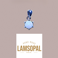 A sterling silver pendant featuring a round, milky white opal gemstone with subtle blue-green flashes, set in a prong setting. The pendant is shown above a white card displaying the brand name 'LAMSOPAL' and the text 'HAND MADE NATURAL OPAL' on a solid taupe background.