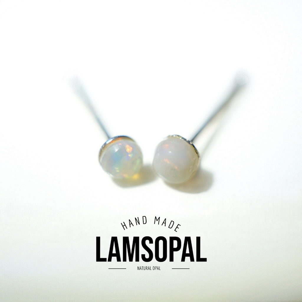 A pair of handmade stud earrings with round, milky white opal gemstones on silver posts, displayed on a clean white background with a 'LAMSOPAL' brand logo overlay at the bottom.