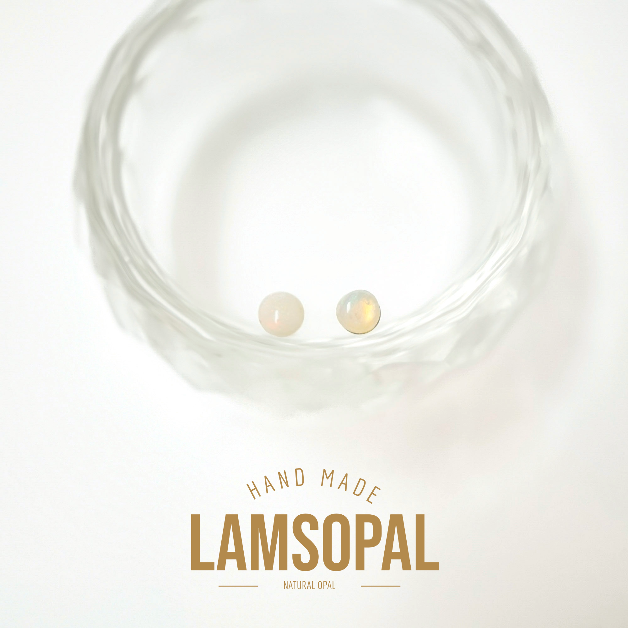 Two small round natural opal gemstones displayed inside a clear textured glass bowl, with the text 'HAND MADE LAMSOPAL NATURAL OPAL' below on a white background.