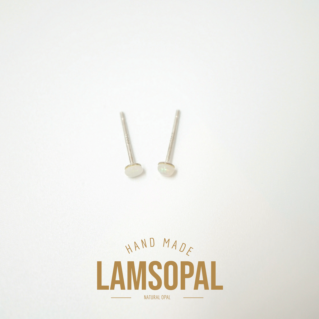 A pair of small natural opal stud earrings with silver posts, displayed on a clean white background with a gold 'LAMSOPAL' brand logo and 'HAND MADE' text below.