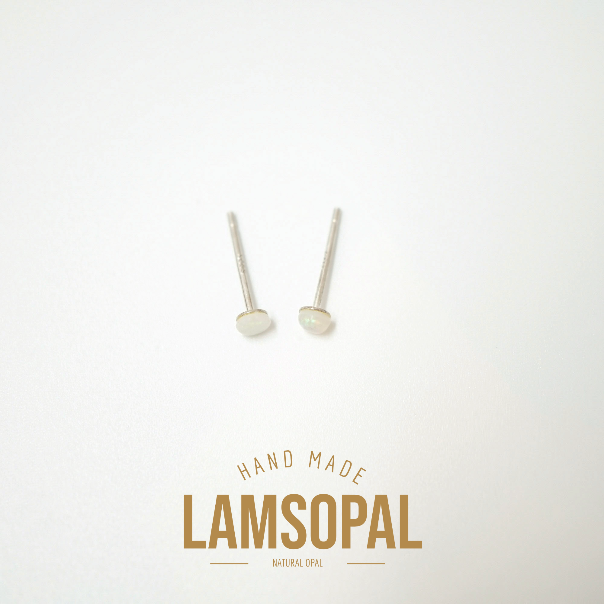 A pair of small natural opal stud earrings with silver posts, displayed on a clean white background with a gold 'LAMSOPAL' brand logo and 'HAND MADE' text below.