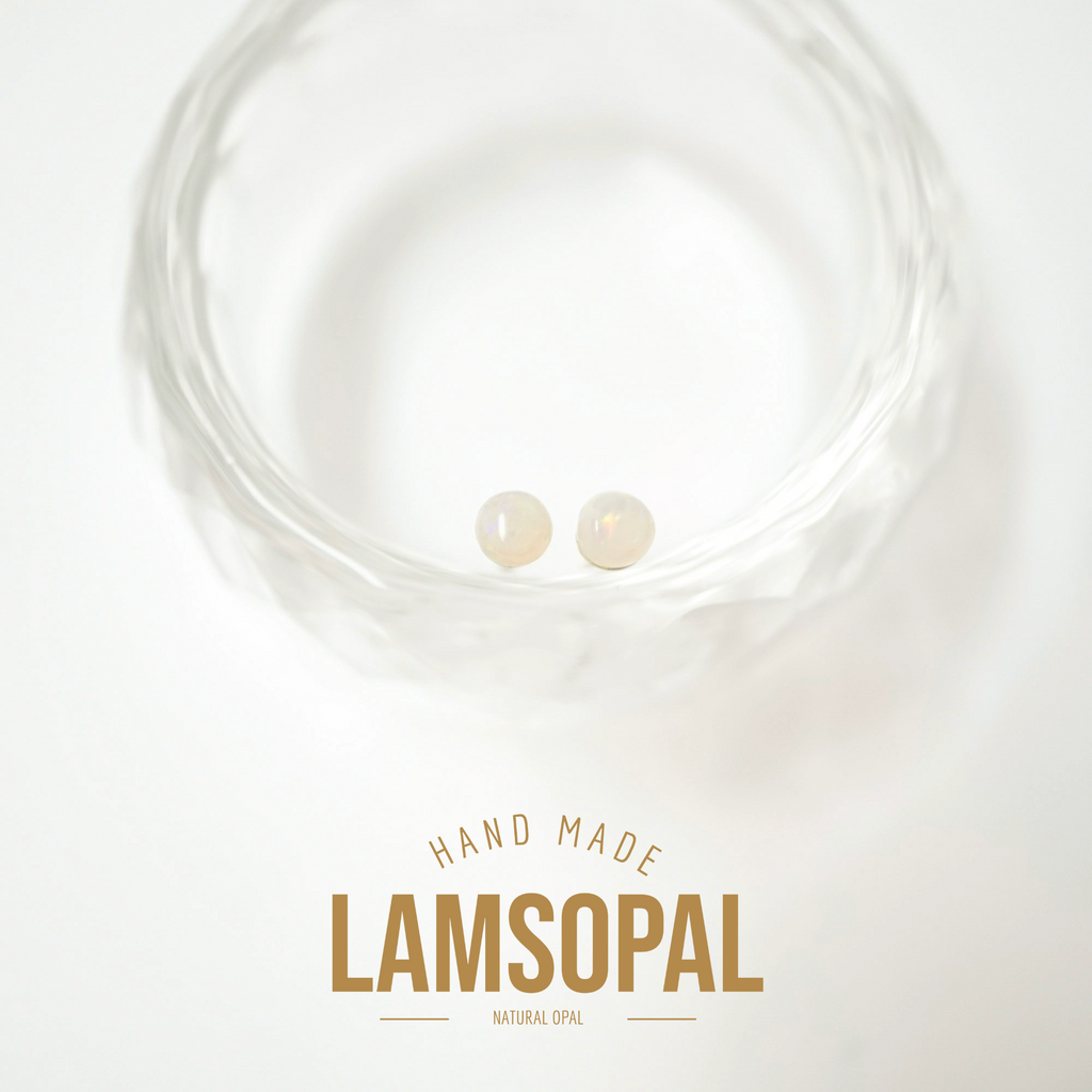 Two small natural opal gemstones displayed inside a clear textured glass bowl, with the text 'HAND MADE LAMSOPAL NATURAL OPAL' below on a white background.