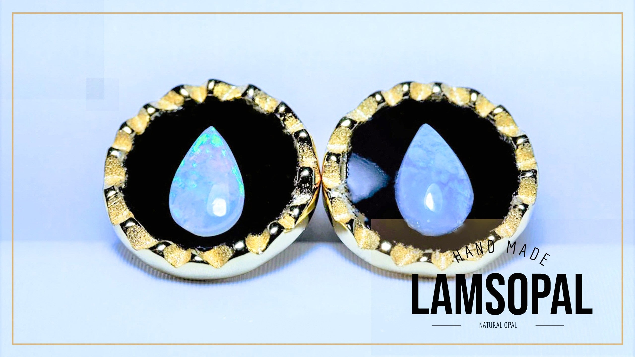 A pair of handmade Lamsopal natural opal teardrop stud earrings with gold bezel settings and black inlay, displayed on a light blue background with a gold border.