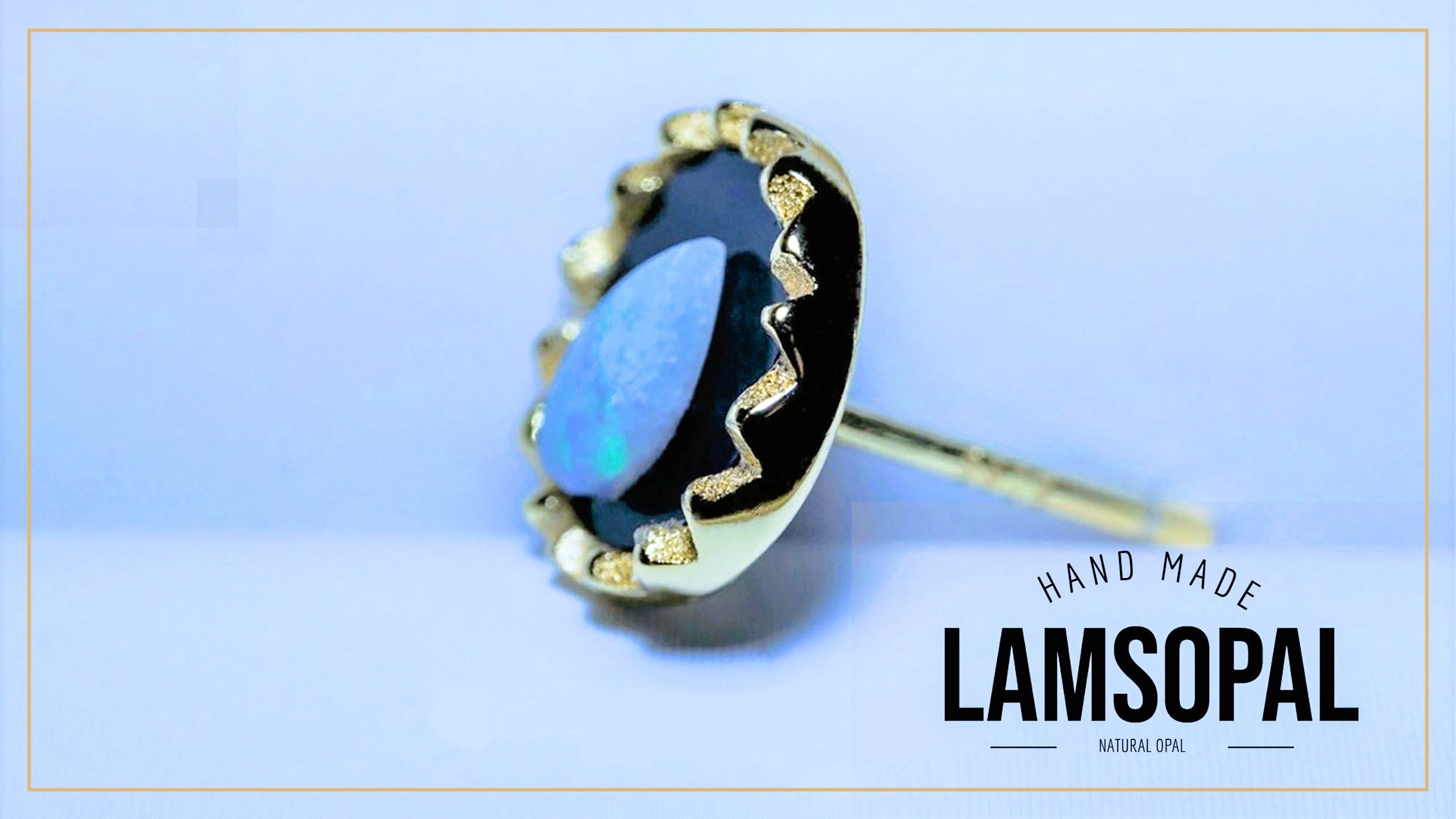 A gold-plated Lamsopal stud earring featuring a natural blue opal gemstone, set against a light blue background with a gold border and a text overlay reading 'HAND MADE LAMSOPAL'.